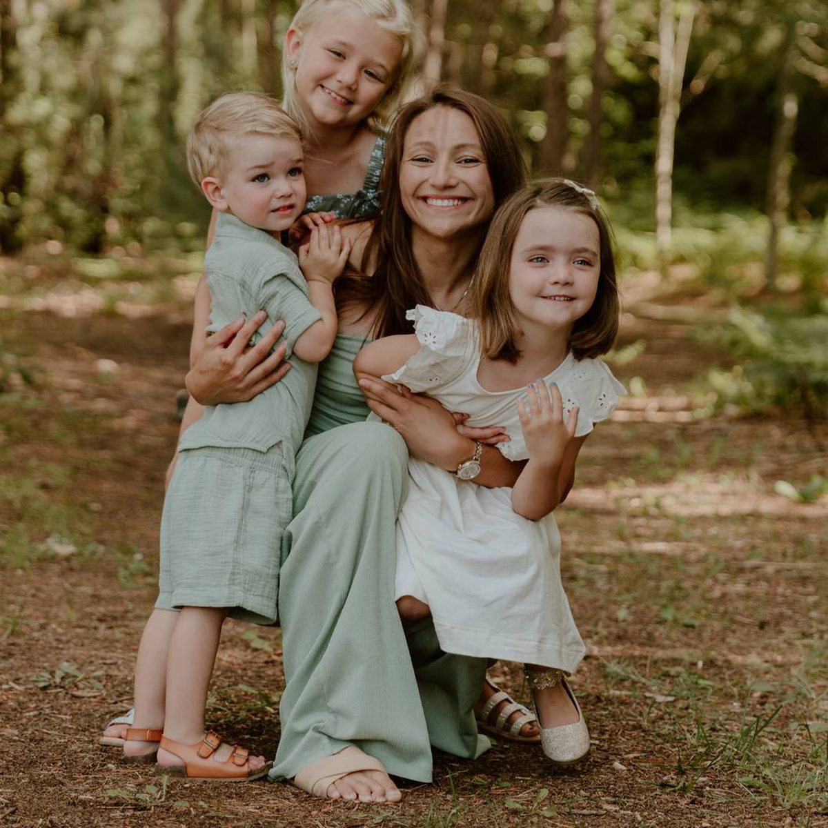 Dr. Abby Maidlow kneeling with three young children in the woods.
