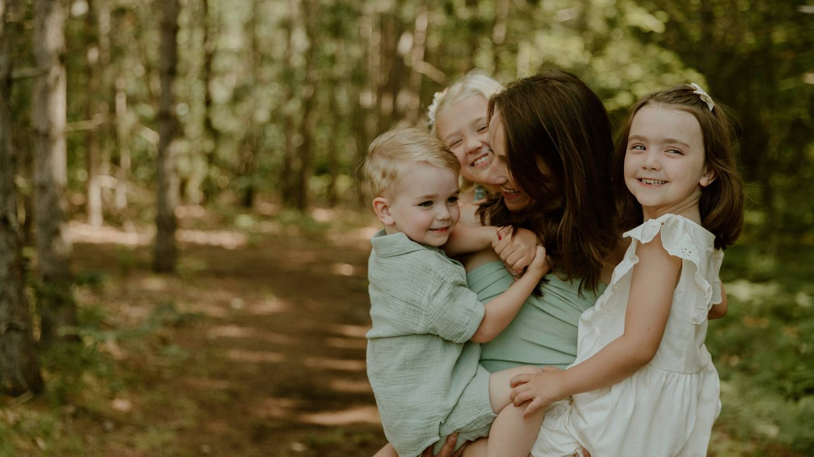 Dr. Abby Maidlow laughing with three young children on a wooded trail.