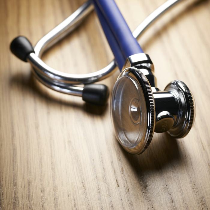 A stethoscope resting on a wooden table.